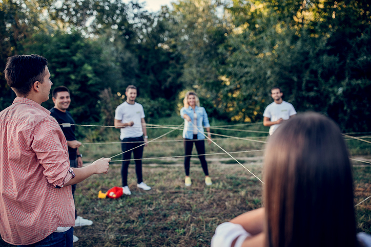 Gruppe junger Menschen spielen Teeamspiel mit Seil