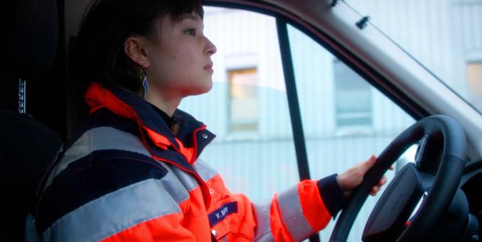 Eine junge Freiwillige fährt den Einsatzwagen. Gemeinsam mit Fachkräften im Rettungs- oder Krankenwagen.