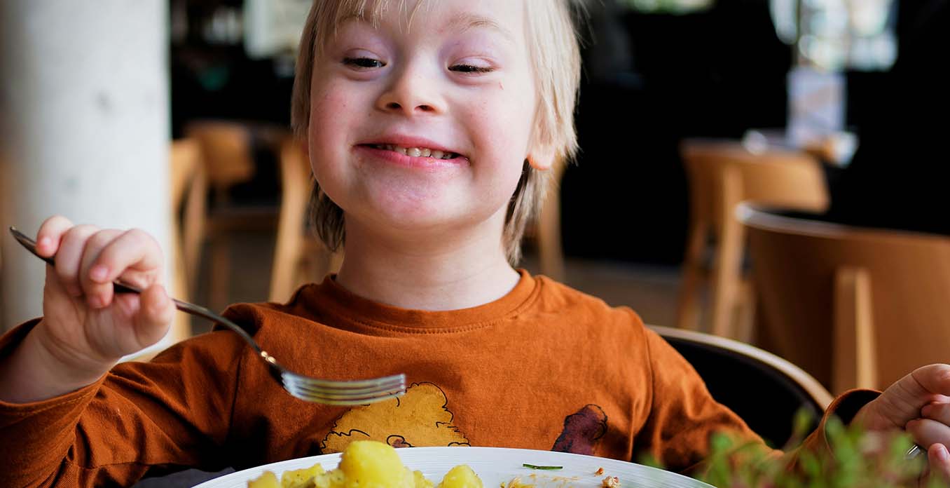 Ein fröhliches Kind isst Mittag.
